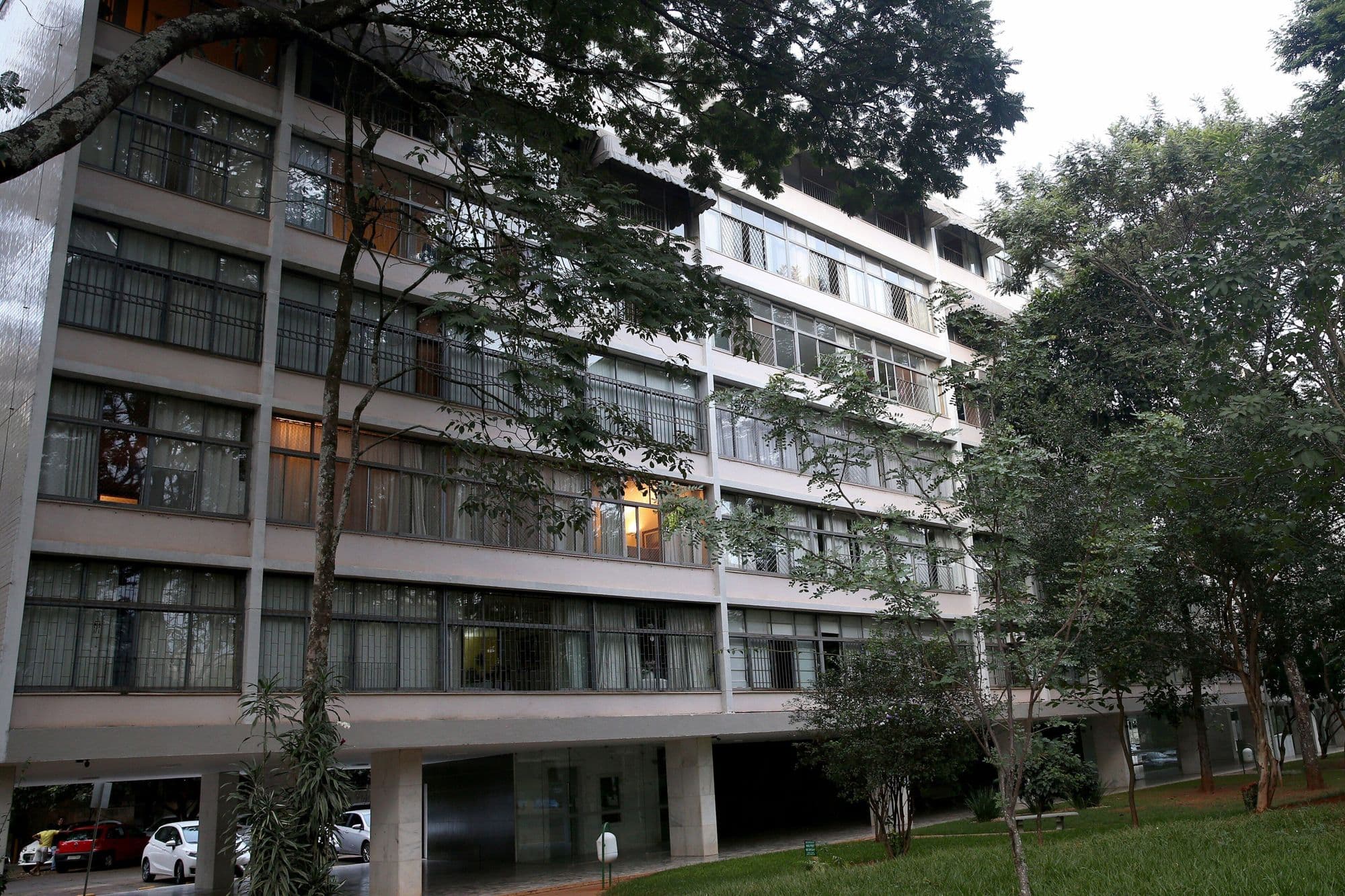 Bloco residencial sobre pilotis numa superquadra de Brasília, entre árvores.